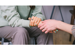 Close up of a person hold the hand of another person demonstrating a gesture of symapthy