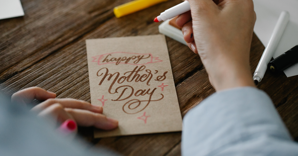 Woman creating Mother's Day card with card stock and markers.