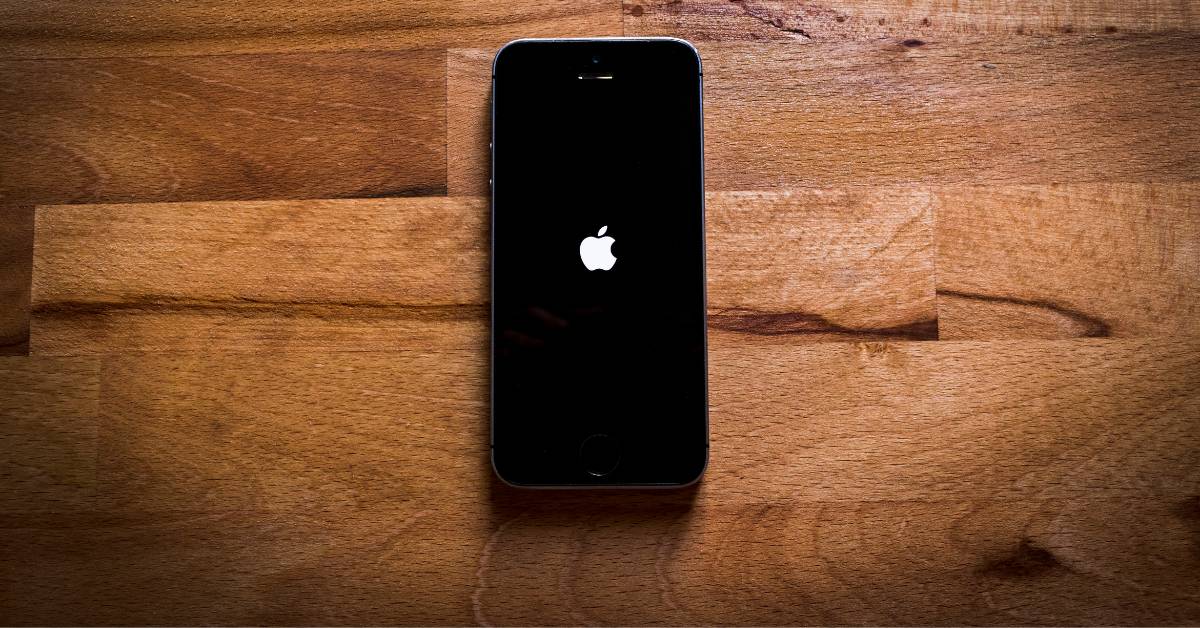 iPhone with loading screen sitting atop wooden table.