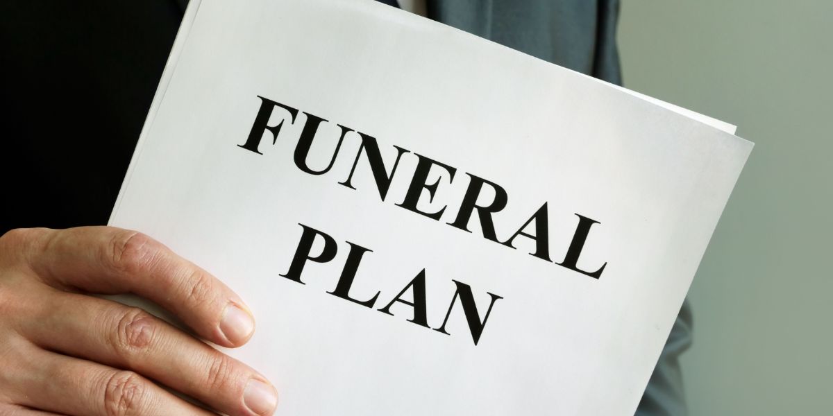 "Funeral Plan" written on a piece of paper being held by a man.