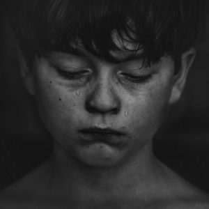 Young boy with tears running down his cheeks.