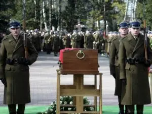 Military personnel standing besides a casket.