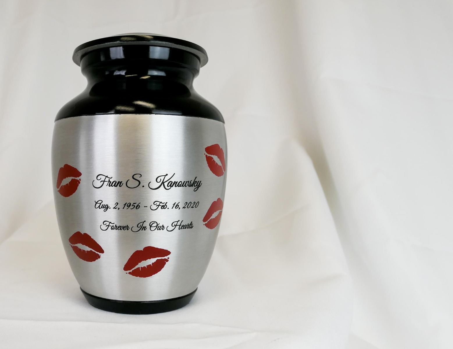 Engraved metal cremation urn with lipstick kiss marks.