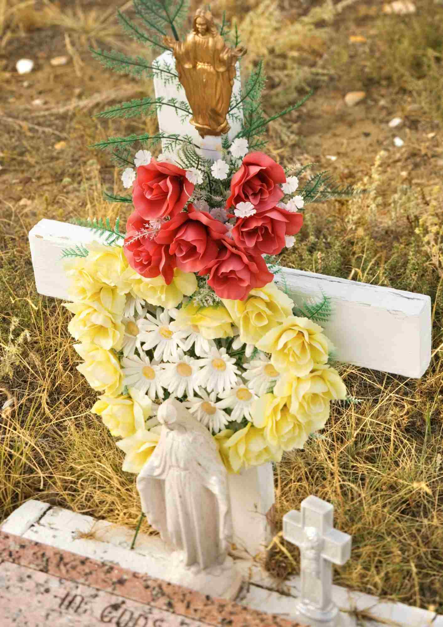 Gravesite decorated with red and yellow flowers.