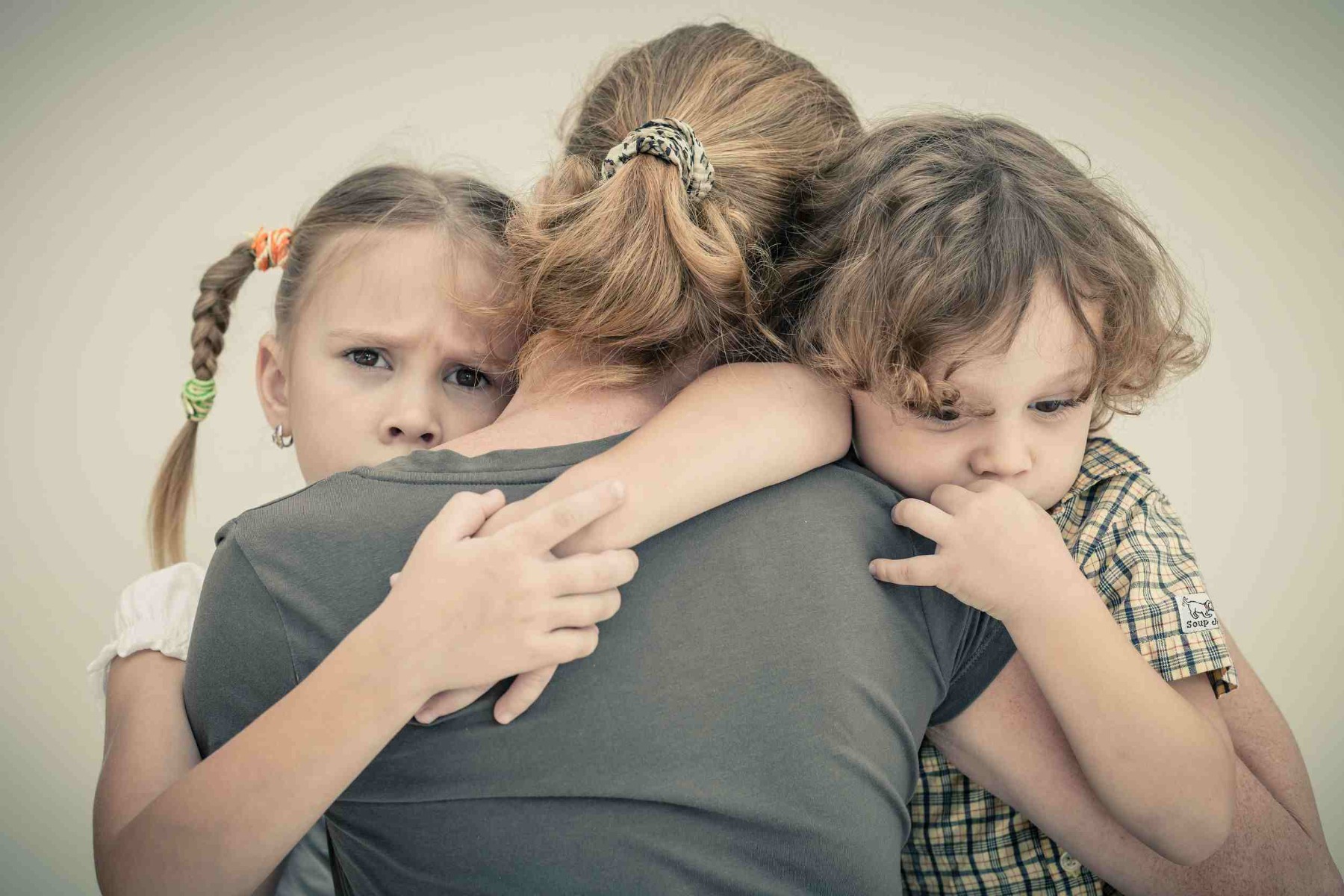 Two children grieving hugging their mother.