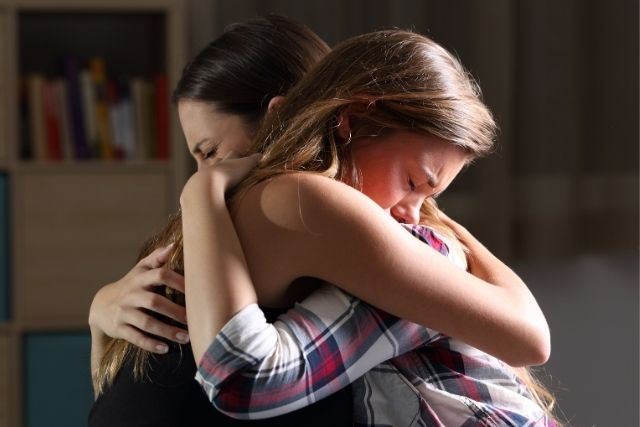 Mother and daughter grieving and hugging.
