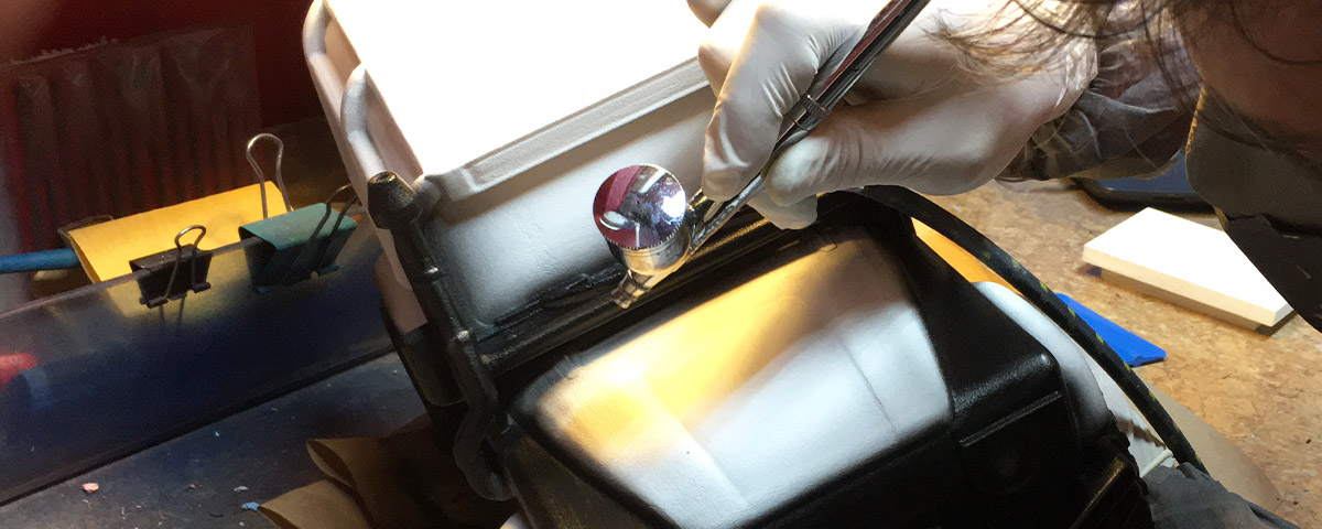 The 3D-printed model of the Land Rover is being airbrushed black.