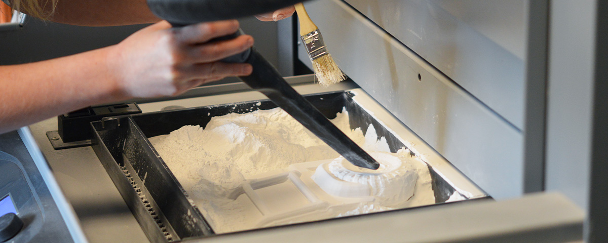 One half of the 3D-printed Land Rover model is inside the powder bed of the 3D printer.