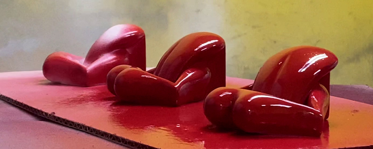 Three tongue and lips 3D prints being painted red.