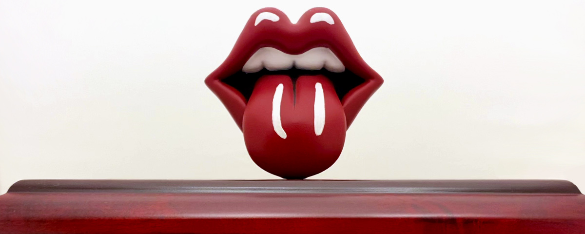 A head-on view of the Rolling Stones' tongue and lips 3D print on top of a wooden urn.
