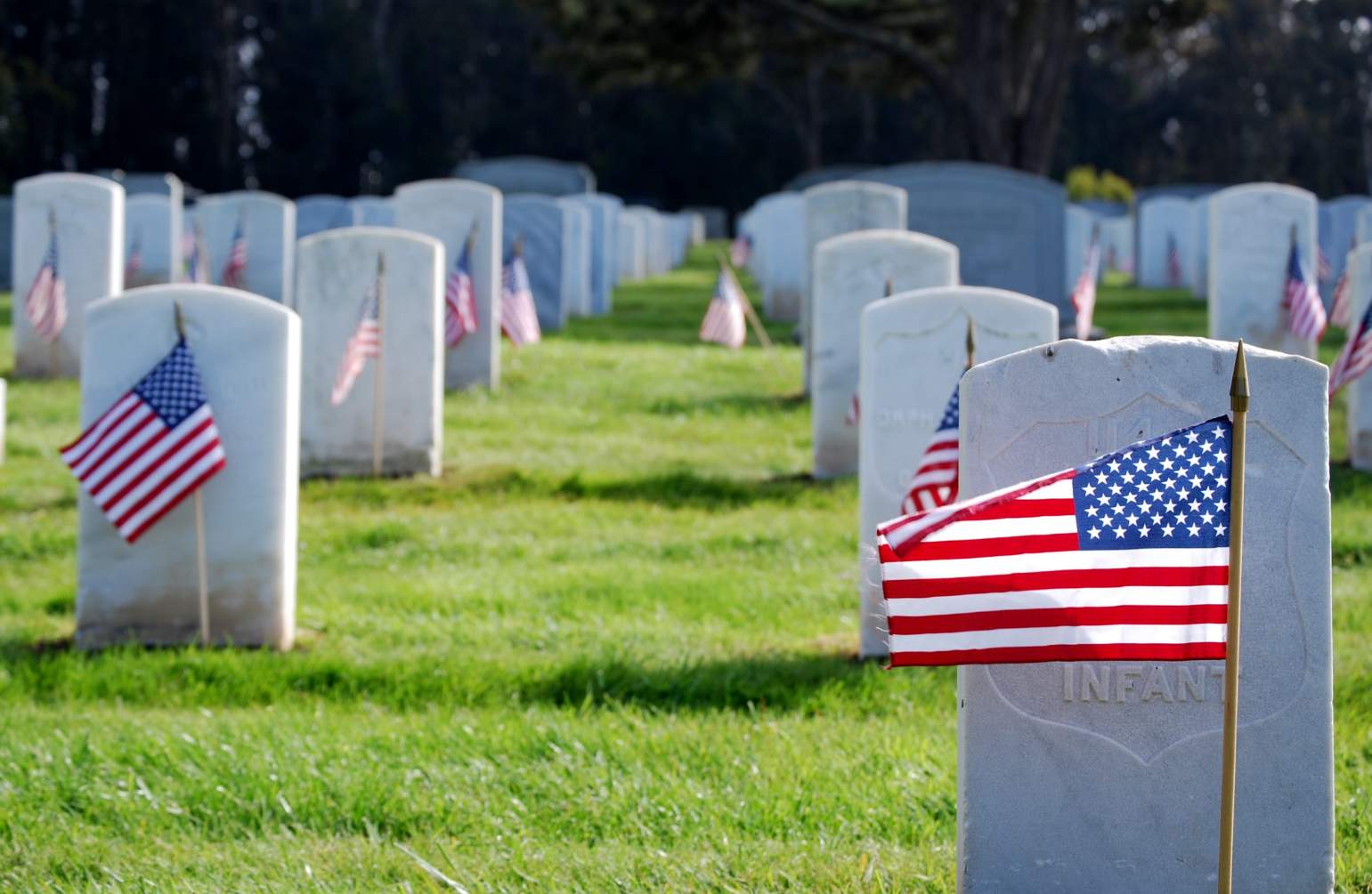 Military cemetery with headstones and small American flags.