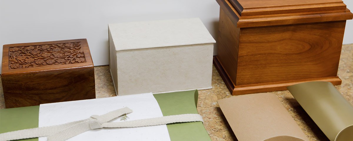 Peaceful Pillow urns are arranged alongside a box-shaped urn and two wooden urns.