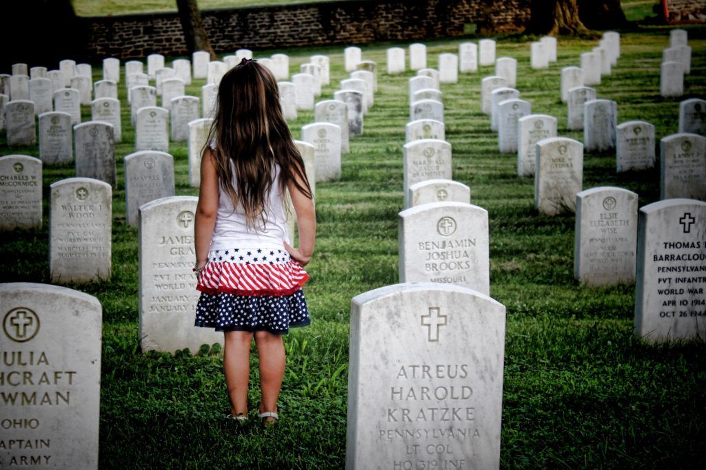 Young girl standing amongst headstones in cemetery.